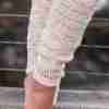 Cream Valley Legwarmer Crochet Pattern from ReVeDesignCo on woman standing - close up against a fence