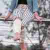 Cream Valley Legwarmer Crochet Pattern from ReVeDesignCos on woman standing - close up sitting on a fence