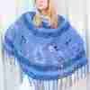 Pineapple Poncho Crochet Pattern – Blue version on Model against white wall with hands on hips Pineapple Poncho Crochet Pattern - Blue version on Model against white wall with hands on hips