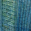 Ocean Layers Wrap Crochet Pattern by ReVeDesignCo - hanging outside with light shining through showing the details - in shades of teal