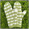 Brindy Mittens Crochet Pattern - in green and white stripes - flat lay on grass