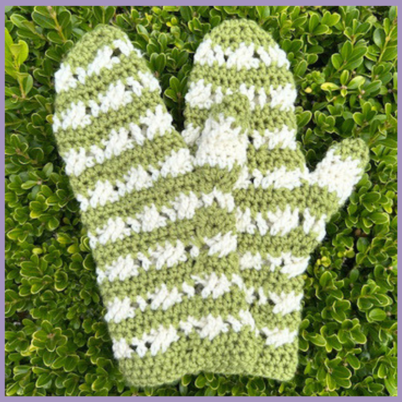 Brindy Mittens Crochet Pattern - in green and white stripes - flat lay on grass